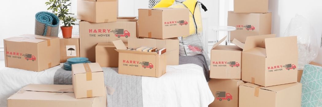 Moving boxes branded with 'Harry The Mover' stacked in a room, ready for relocation in Melbourne.