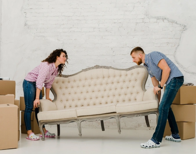 Couple lifting a sofa during house move with boxes – Furniture Removalists Adelaide.