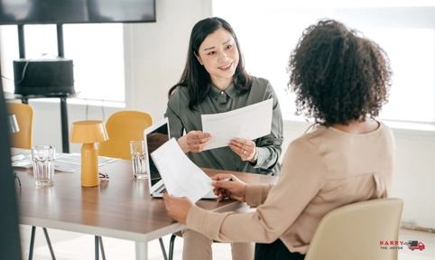 Questions to ask moving companies with women discussing paperwork and relocation services.